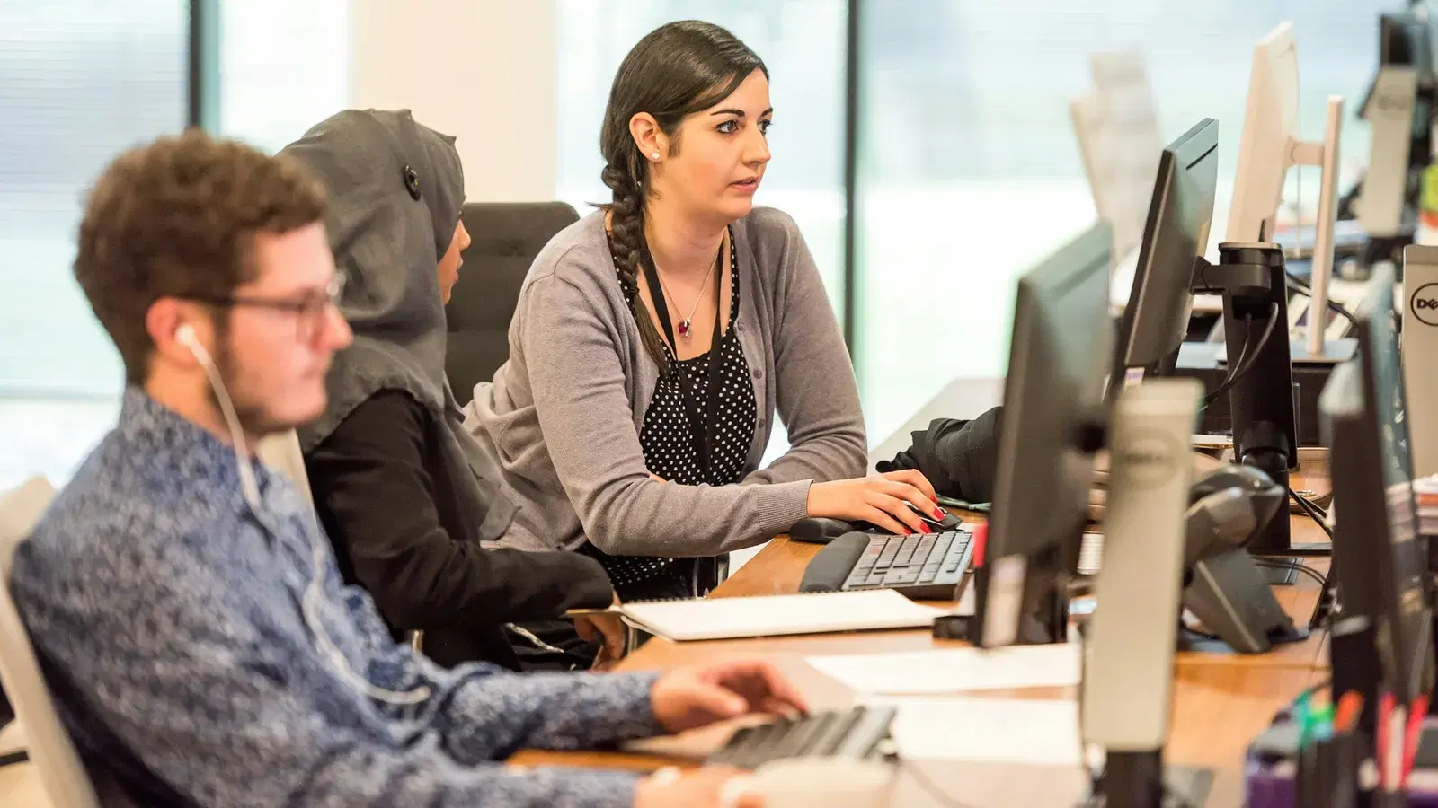 Support team working side by side at office monitors handling customer messages
