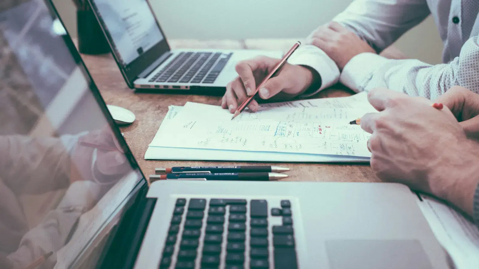 Two people reviewing a business verification application document at a desk